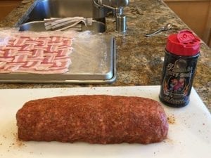 Applying barbecue rub to sausage log